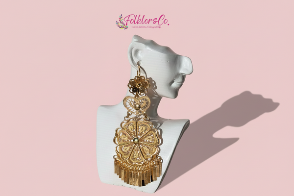 Gold earrings on a mannequin ear with 'Folkloryco' branding on a pink background