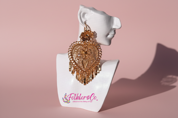 Gold Mexican Folklorico earrings on a white mannequin head with 'Folkloryco.' branding on a pink background
