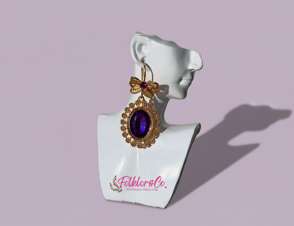 Mexican gold earring with purple gemstone on a white mannequin bust with 'Folkloryco' branding.