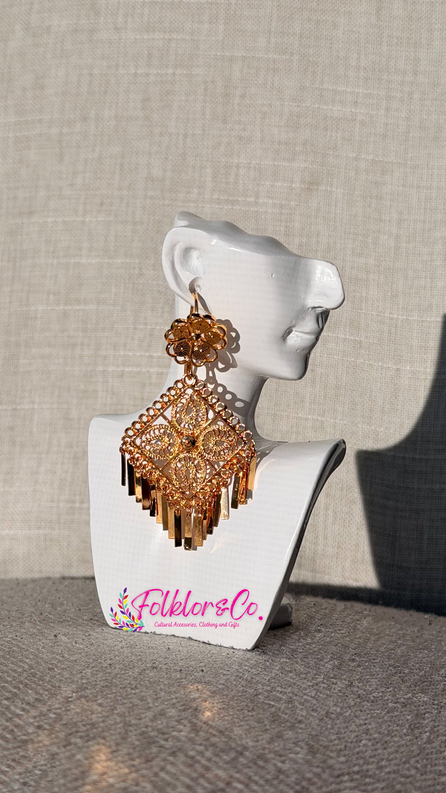 Gold Mexican filigrana earrings on a white mannequin bust with 'Folkloryco' branding against a beige background.