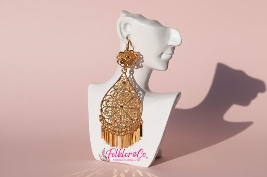 Gold earrings on a white mannequin bust with 'Folklorico' branding on a pink background