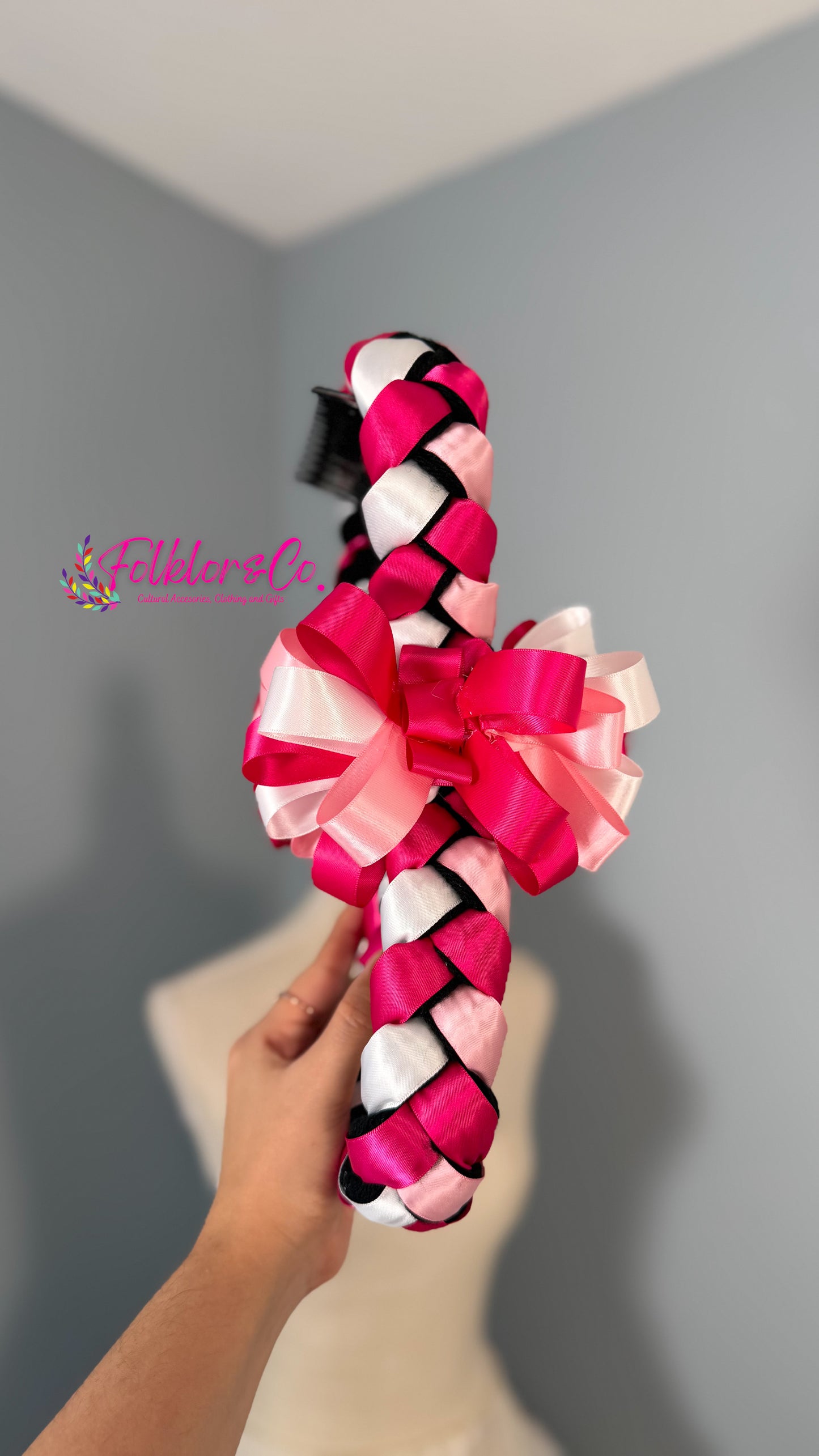 Hand holding a colorful braided Jalisco trenza against a gray background